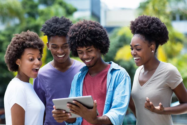 Group of african american young adults shopping online with digital tablet outdoor in the summer