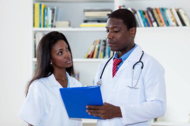 Afro-Amerikan erkek doktor hemşire ile hasta hakkında konuşmak