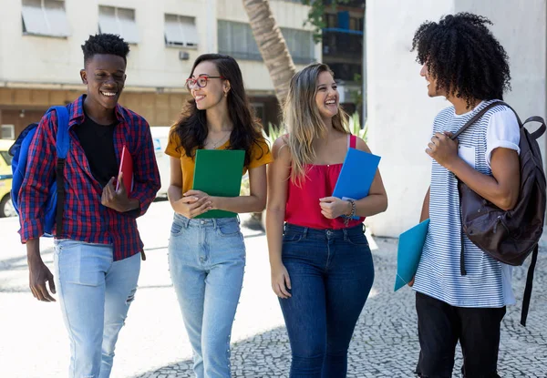 Quatro jovens estudantes internacionais caminhando para a universidade — Fotografia de Stock