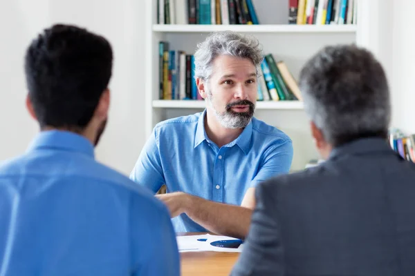Homem de negócios adulto maduro com barba conversando com colegas — Fotografia de Stock