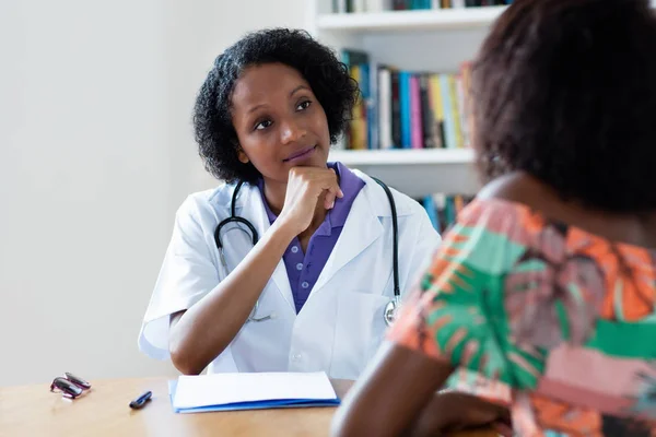 Афроамериканець жіночий лікар слухає пацієнта — стокове фото