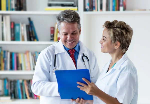 Laughing mature general practitioner with female doctor at work — Stock Photo, Image