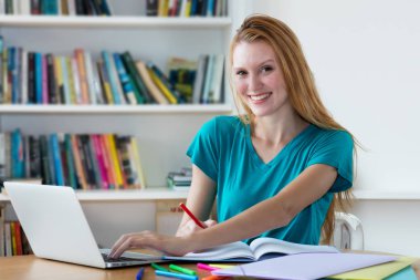 Gülen Alman kız öğrenci bilgisayarda öğrenme