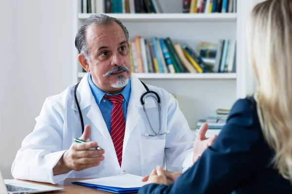 Senior doctor explaining treatment to female patient — Stock Photo, Image