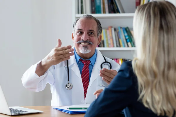 Laughing doctor explaining medical treatment to female patient — Stock Photo, Image