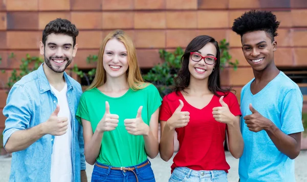 Група з чотирьох молодих людей покоління y, що показують великі пальці — стокове фото