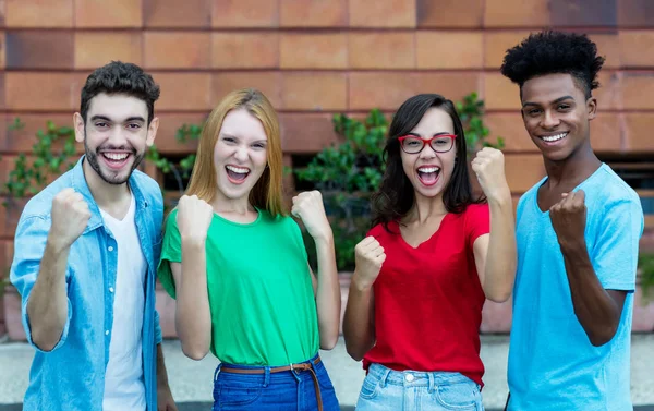 Grupo de torcida de quatro jovens adultos da geração y mostrando thum — Fotografia de Stock