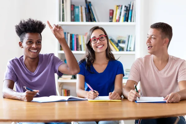 Africano americano estudante do sexo masculino levantando a mão em sala de aula de schoo — Fotografia de Stock