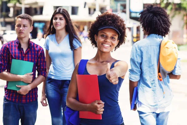 Lachende junge erwachsene afrikanisch-amerikanische Frau mit Studenten in Zitat — Stockfoto