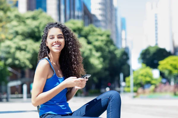 Γέλια νεαρή ενήλικη γυναίκα στέλνοντας μήνυμα με το τηλέφωνο στην πόλη — Φωτογραφία Αρχείου