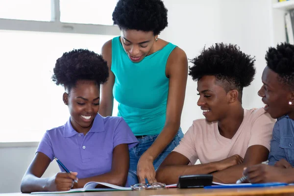 Laughing african american students with mature female teacher — Stock Photo, Image