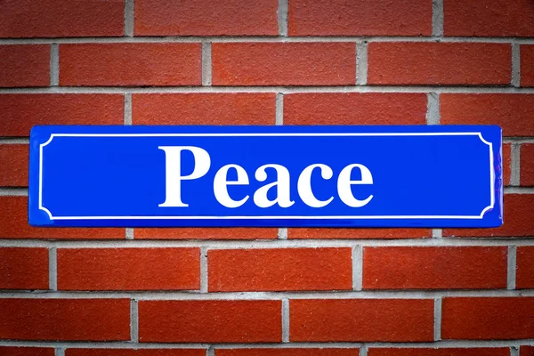 Paz sinal de rua na parede de tijolo — Fotografia de Stock