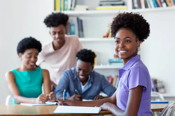 Смеющаяся африканская студентка-американка учится за столом в школе — стоковое фото