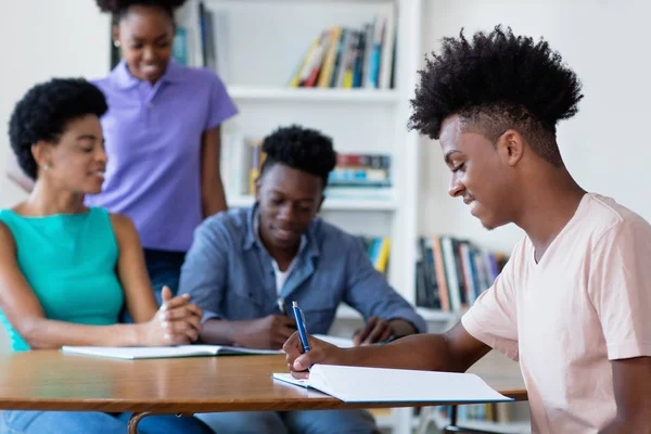 Inteligente afro-americano estudante do sexo masculino aprendendo na mesa na escola — Fotografia de Stock