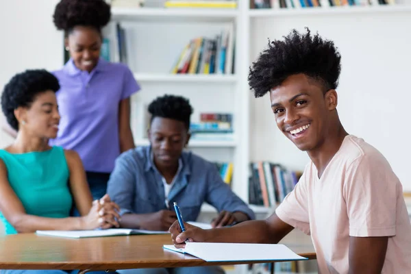 Молодой африканский американец, учащийся мужского пола, учится за столом в школе — стоковое фото