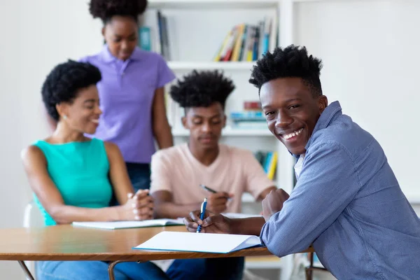 Afroamericano maschio studente apprendimento a scrivania a scuola — Foto Stock