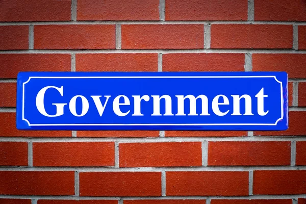 Government street sign on brick wall — Stock Photo, Image