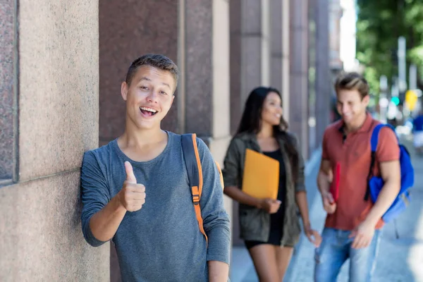 Homem adulto jovem caucasiano na cidade com grupo de estudantes — Fotografia de Stock
