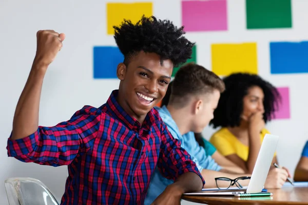 Jubelnder afrikanisch-amerikanischer Student am Computer mit einer Gruppe von — Stockfoto