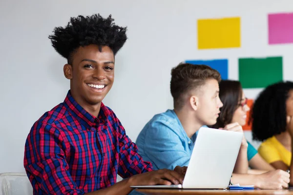Africano americano estudante do sexo masculino no computador com grupo de estudantes — Fotografia de Stock