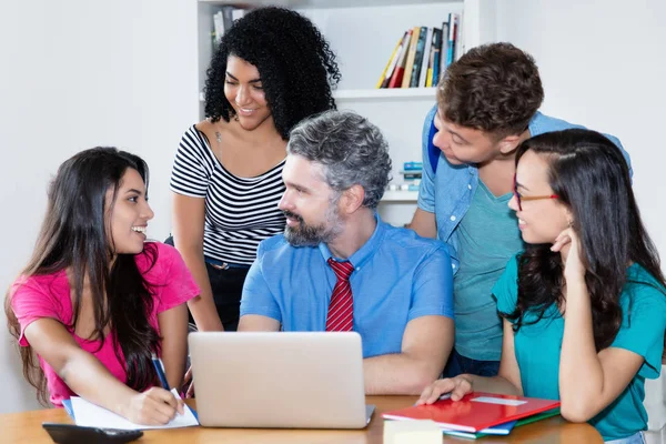 Volwassen mannelijke leraar met groep van multi etnische College studenten — Stockfoto