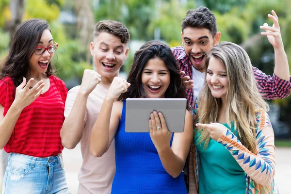 Jublande kvinnlig elev med Tablet PC och grupp av cheeri — Stockfoto
