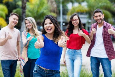 Gülen Meksikalı kadın genç adul grubu ile başparmak gösteren