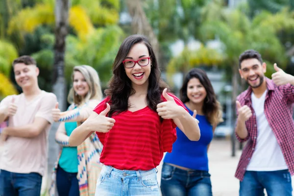 Francese donna con gli occhiali mostrando pollice in su con gruppo di giovani un — Foto Stock