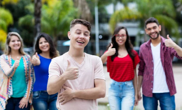 Tysk ung vuxen visar tummen upp med grupp vänner — Stockfoto