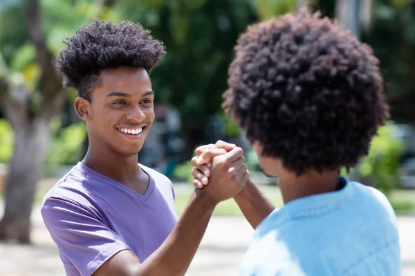 Afro-americano jovem adulto homem dá alta cinco para amigo com — Fotografia de Stock