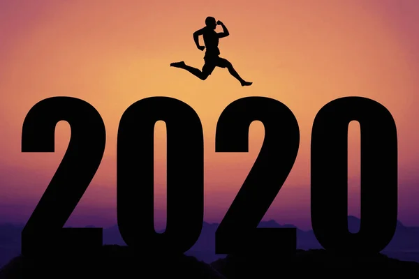 Sunset with new year 2020 and silhouette of jumping man — Stock Photo, Image