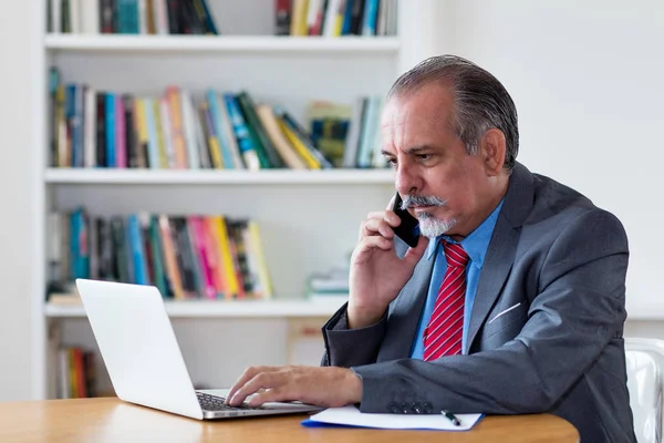 Senior affärsman med kostym och telefon och dator — Stockfoto