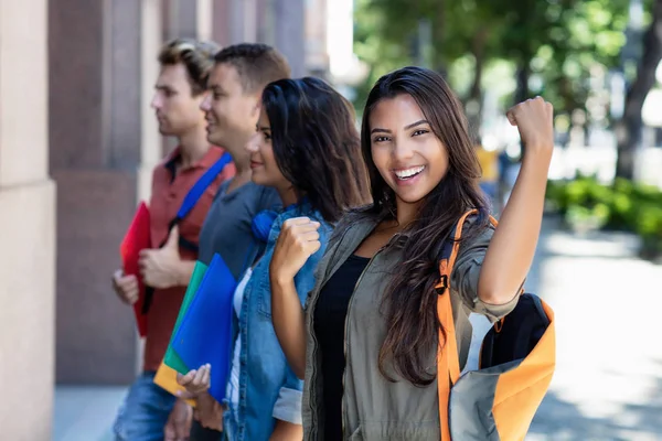 Bem sucedida torcida latino-americano estudante do sexo feminino com grupo de — Fotografia de Stock