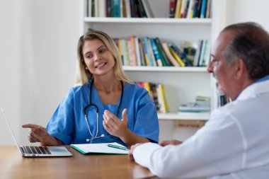 Güzel sarışın hemşire doktorla konuşuyor.