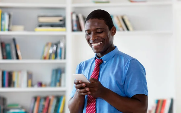 Empresário afro-americano enviando mensagem com celular — Fotografia de Stock