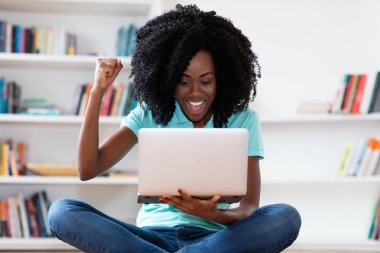 Afrikalı Amerikalı kadın bilgisayarla online alışveriş yapıyor.