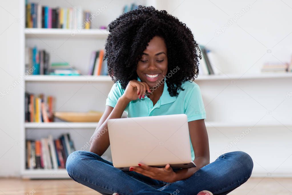 Laughing african american woman watching movie online with compu