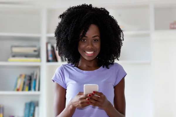 Lachender Afroamerikaner sendet Nachricht mit Handy — Stockfoto