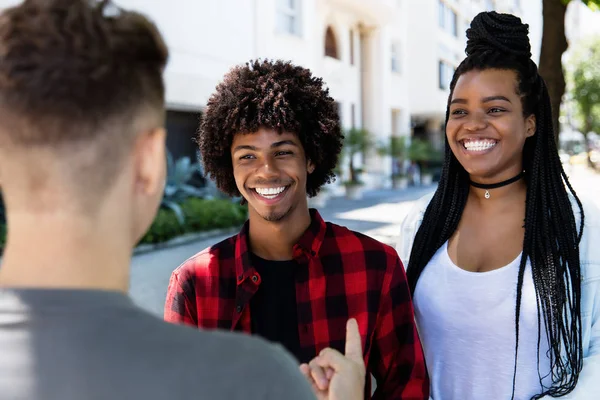 Afro-Amerikan erkek ve kadın Latin genç bir yetişkinle konuşuyor. — Stok fotoğraf