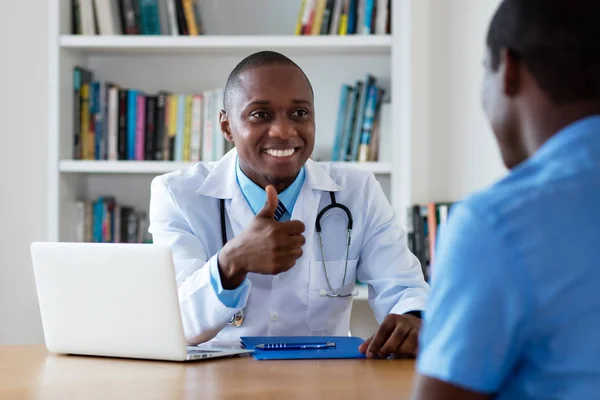 Riéndose médico afroamericano tiene buenas noticias para el paciente masculino — Foto de Stock
