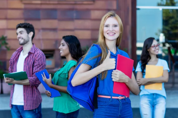 Jubelnde Studentin mit roten Haaren und Gruppe junger Erwachsener — Stockfoto