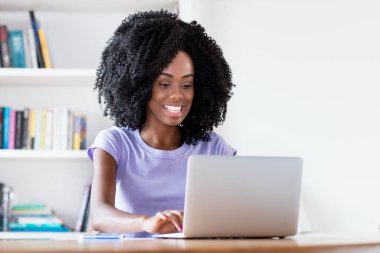 Evdeki karantinadaki bilgisayarda karantinaya alınan Afrikalı Amerikalı bir kadının gülüşü.
