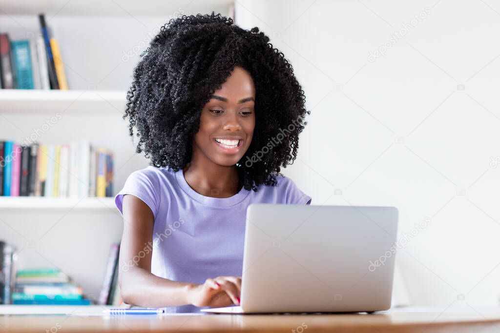 Laughing african american woman in quarantine at video call at computer in quarantine indoors at home