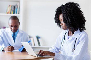 Hastanedeki erkek doktorla bilgisayardaki Afrikalı Amerikalı tıp öğrencisi.