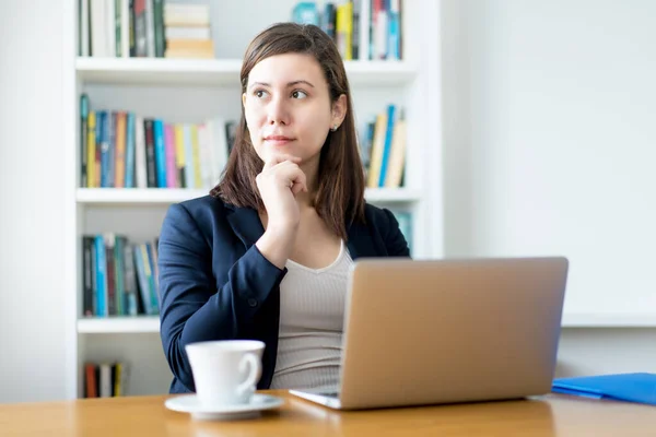 Thinking caucasian businesswoman at computer at office