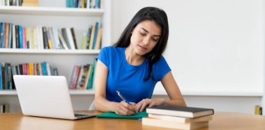 Evdeki ya da kütüphanedeki masada oturan güzel Türk bayan öğrenci