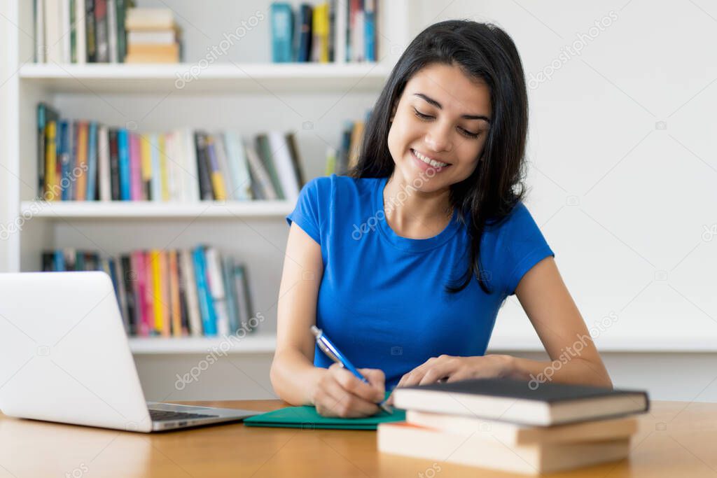 Young turkish female student at desk at home or at library
