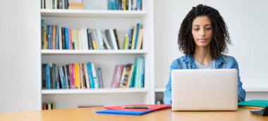 Bilgisayarda kıvırcık saçlı, evinde fotokopi masası olan güzel Latin kız öğrenci.