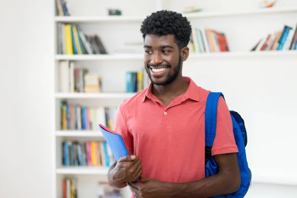 ハンサムなアフロ系アメリカ人男性学生でバックパック付きで大学の図書館 — ストック写真