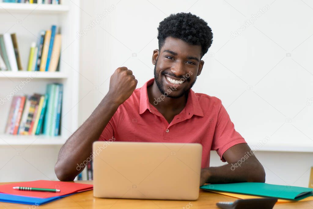 Successful afro american male student learning at computer indoors at home
